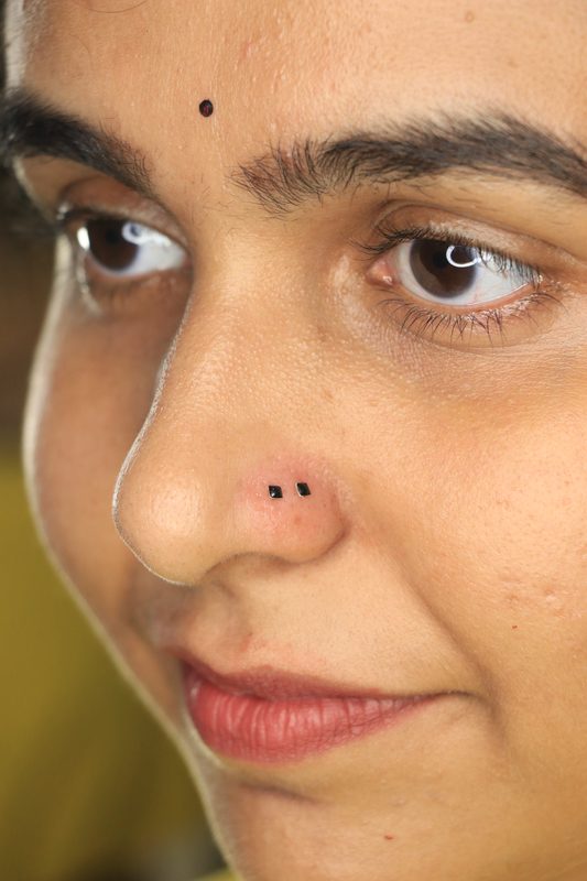 Double nostril piercing with black studs