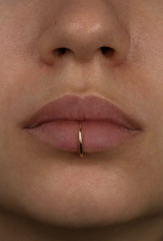 Lower lip ring labret piercing with gold hoop