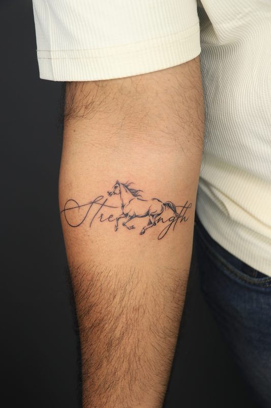 Strength script tattoo with running horse on forearm