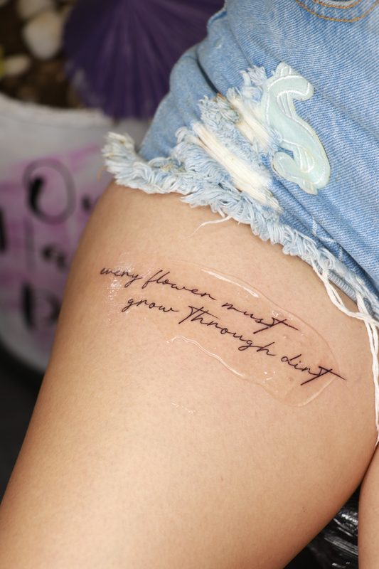 Every flower must grow through dirt thigh script tattoo