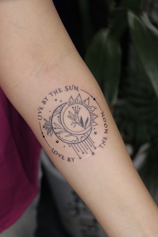 Live by the sun love by the moon circular script tattoo
