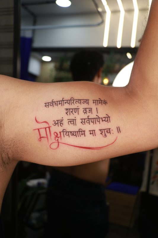 Sanskrit Gita shloka script tattoo with moksha in red