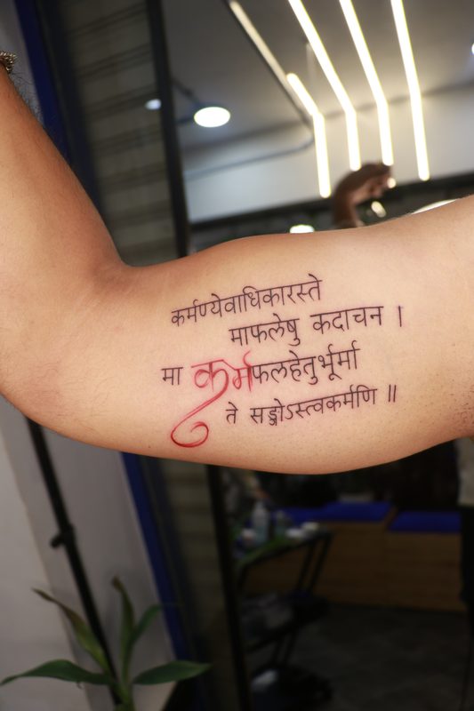 Karmanyevadhikaraste Sanskrit shloka tattoo with karma in red